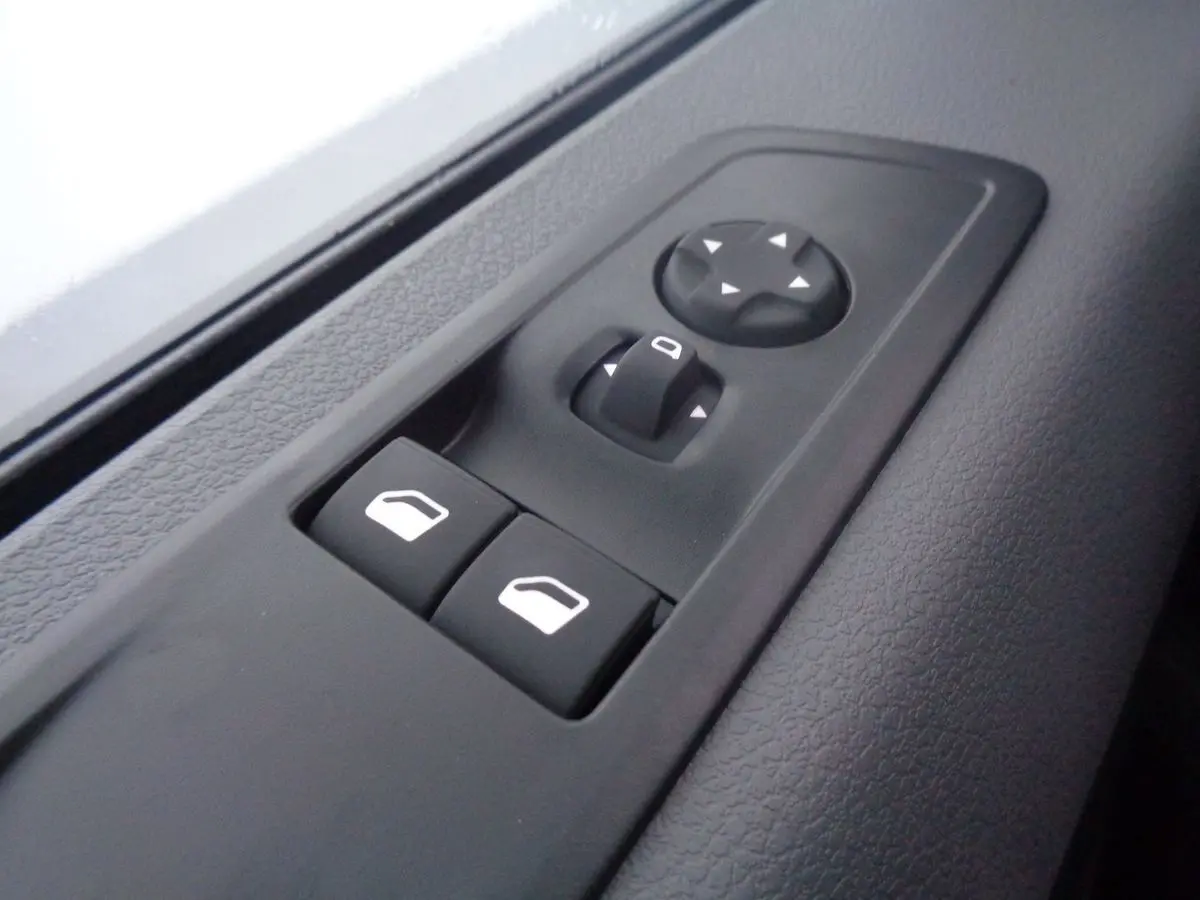 Gros plan sur les commandes de lève-vitres et réglage des rétroviseurs côté conducteur du Peugeot Expert Fourgon noir métal 2022.