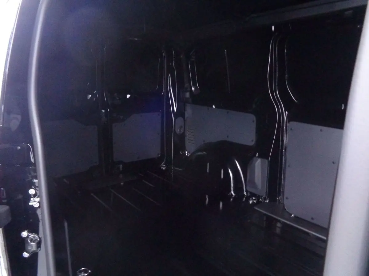 Intérieur du fourgon Peugeot Expert Standard noir métal, vue depuis la porte latérale ouverte montrant l'espace de chargement vide.
