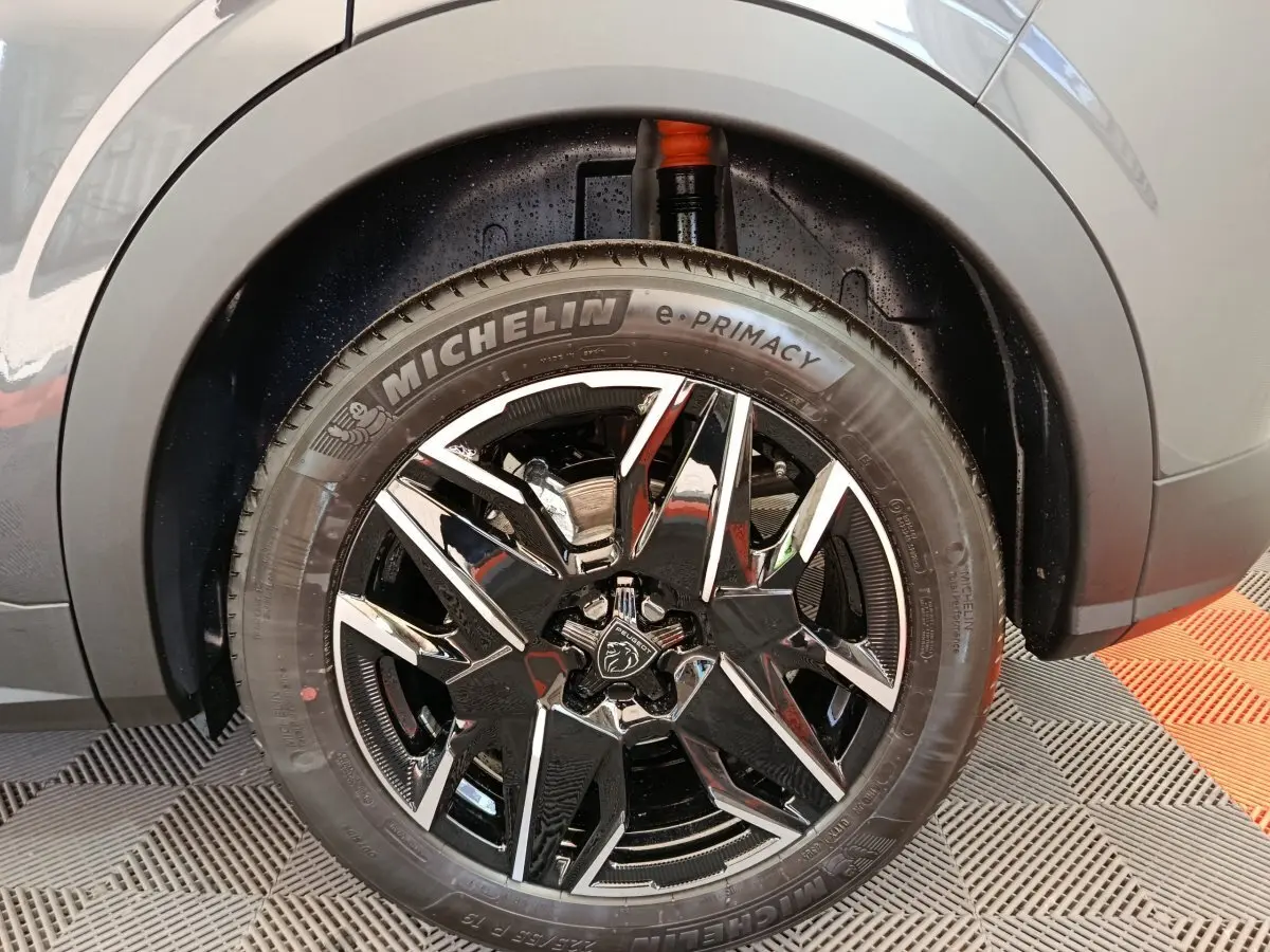 Gros plan sur la roue avant gauche du Peugeot 3008 gris foncé, mettant en valeur la jante noire brillante et le pneu Michelin e-Primacy.