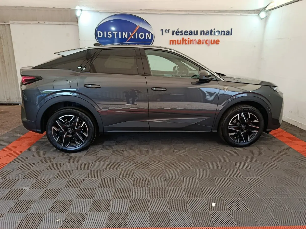 Profil droit du Peugeot 3008 gris foncé 1.2 HYBRID 145 GT en intérieur avec jantes noires et logo distinctif sur aile avant.