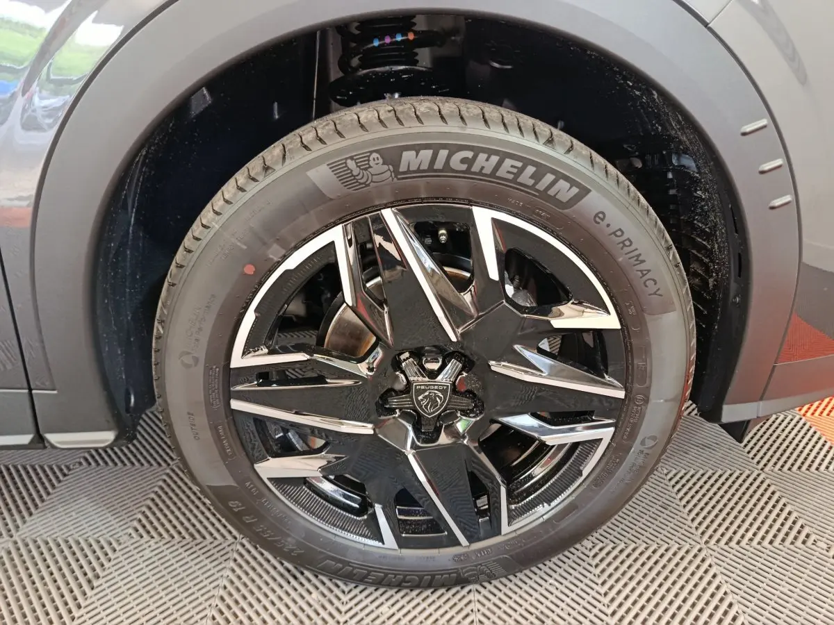 Gros plan sur la roue avant gauche gris foncé du Peugeot 3008 1.2 Hybrid 145 GT avec jante noire et détails chromés.