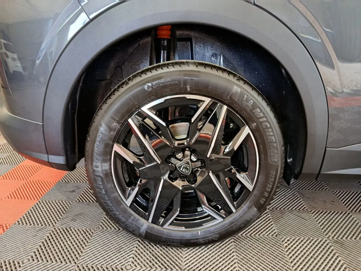 Gros plan sur la roue avant droite du Peugeot 3008 gris foncé, jante alliage noire et détails Michelin visibles.