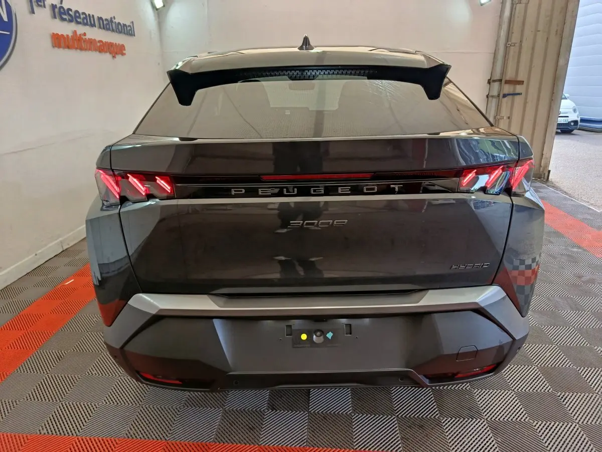 Vue arrière d'un Peugeot 3008 gris foncé hybride 2025 avec feux LED distinctifs et hayon fermé dans un garage.