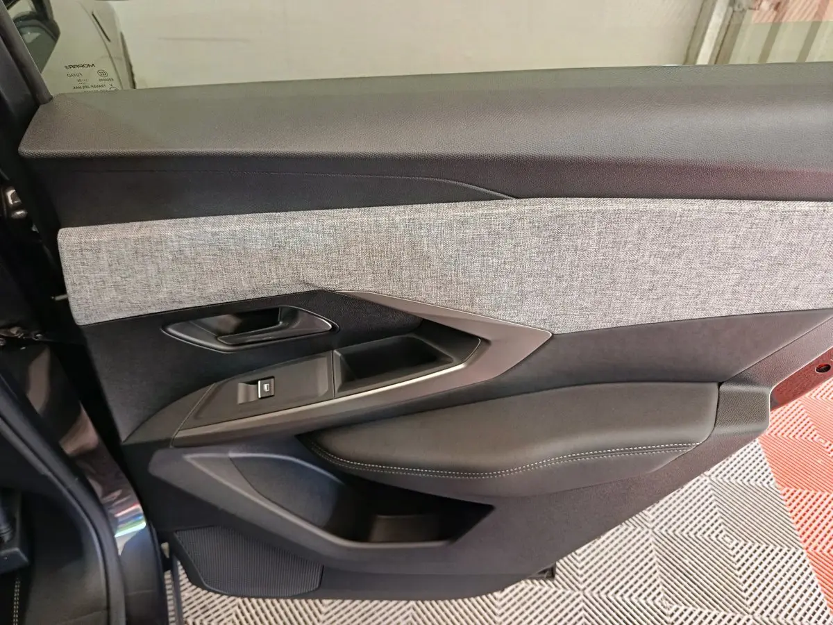 Porte côté gauche intérieur du Peugeot 3008 gris foncé, avec garniture tissu clair et accoudoir en cuir noir.
