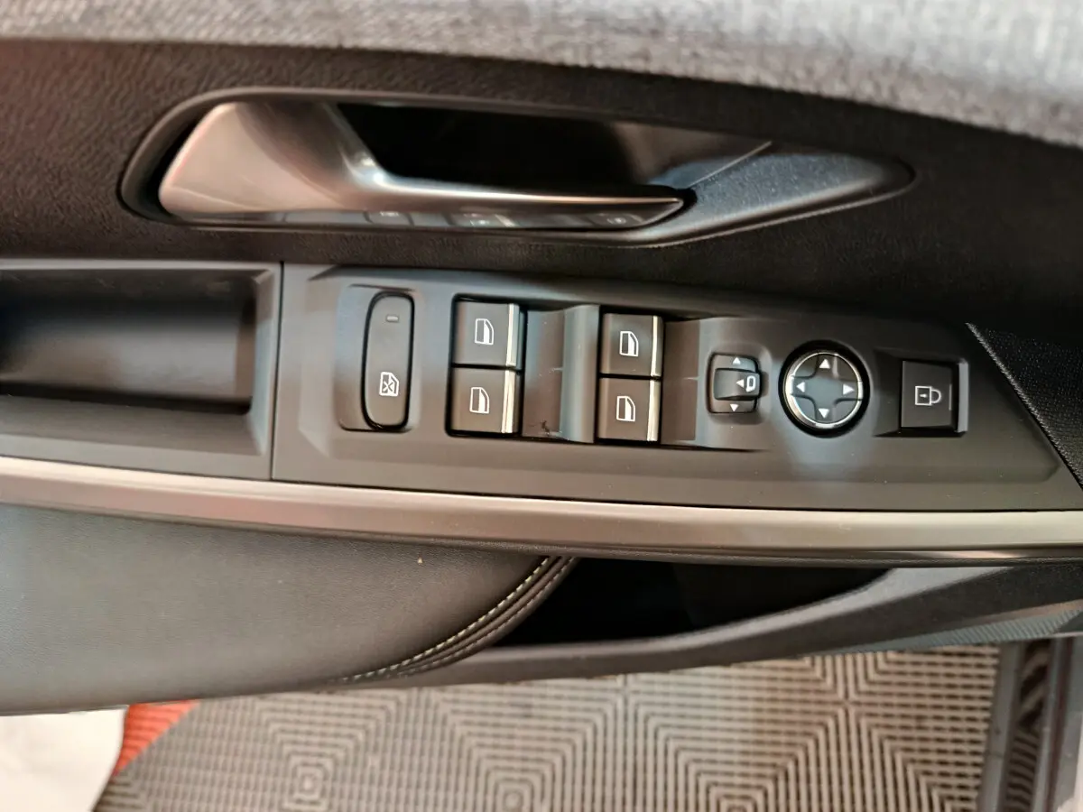 Gros plan sur la commande des vitres et rétroviseurs côté gauche d'une Peugeot 3008 gris foncé 2025.