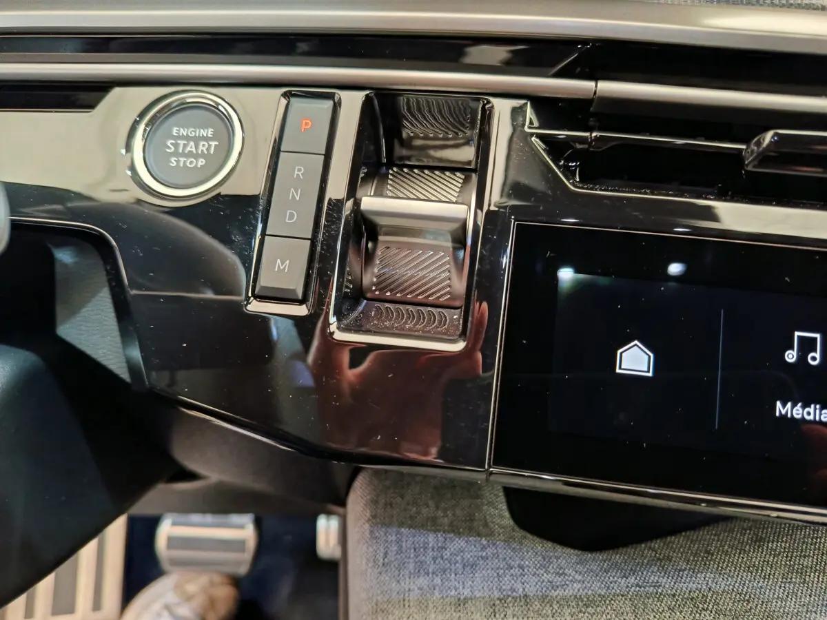 Détail de la console centrale noire brillante du Peugeot 3008 hybride 2025 avec bouton start/stop et commandes de boîte automatique.