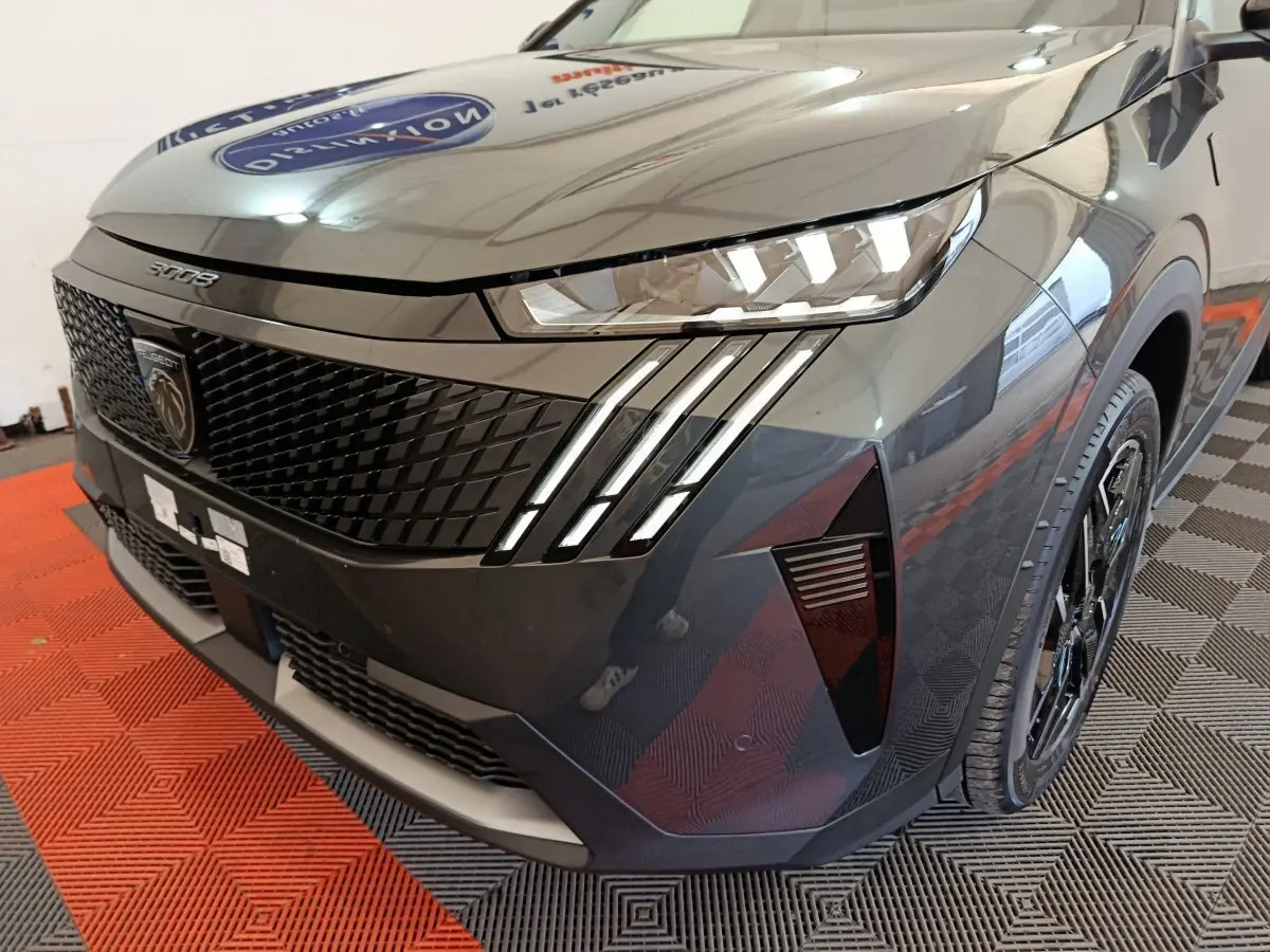 Vue 3/4 avant droit du Peugeot 3008 gris foncé mettant en valeur ses phares LED et sa calandre distinctive.