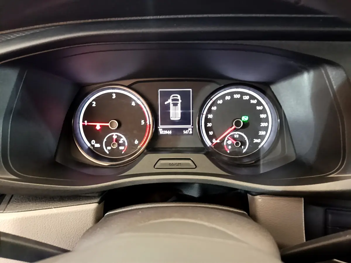 Vue rapprochée du tableau de bord du Volkswagen Transporter blanc, affichant compte-tours et vitesse avec écran central numérique.