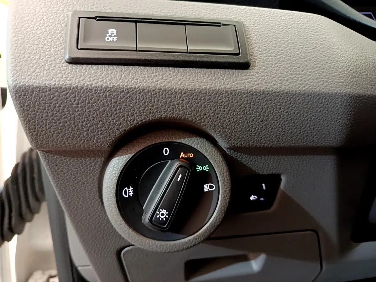 Gros plan sur la commande des phares du Volkswagen Transporter 2.0 TDi blanc, avec réglage automatique et antibrouillard.