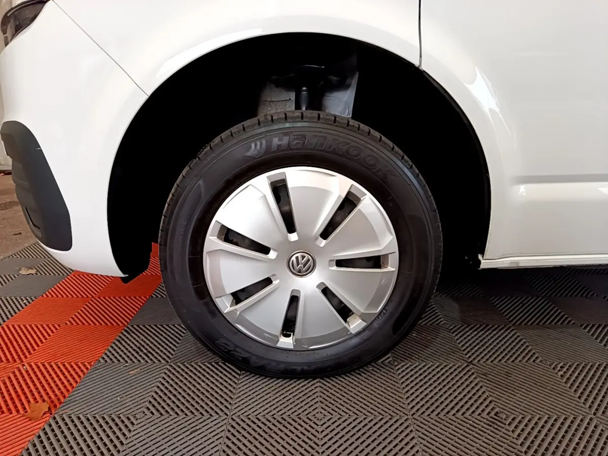 Gros plan sur la roue avant gauche blanche d’un Volkswagen Transporter 2.0 TDi 150 DSG7 avec enjoliveur argenté.