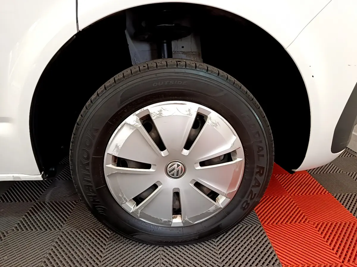Gros plan sur la roue avant gauche blanche d’un Volkswagen Transporter 2.0 TDi 150 DSG7 avec jante acier et enjoliveur abîmé.