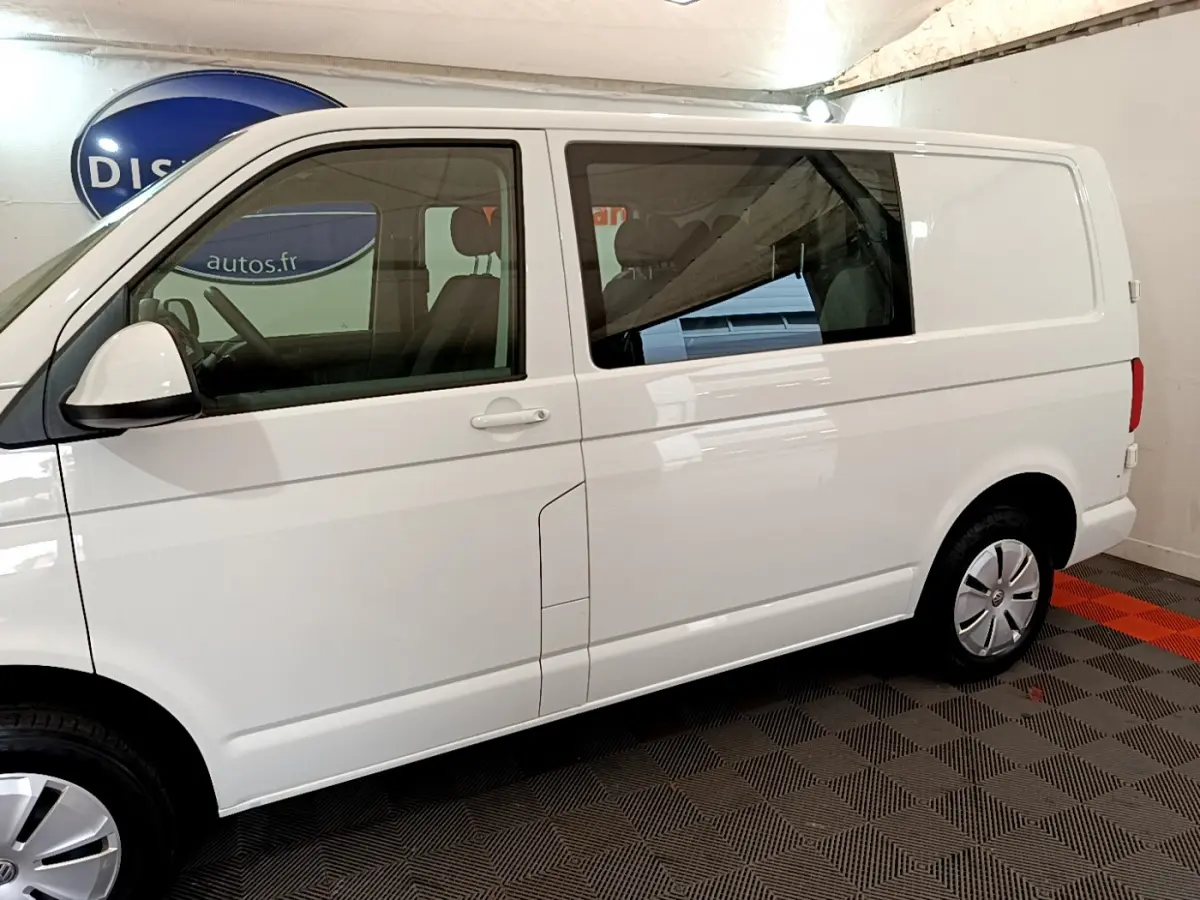 Vue de profil côté gauche du Volkswagen Transporter blanc 2.0 TDi avec vitres teintées et jantes acier.