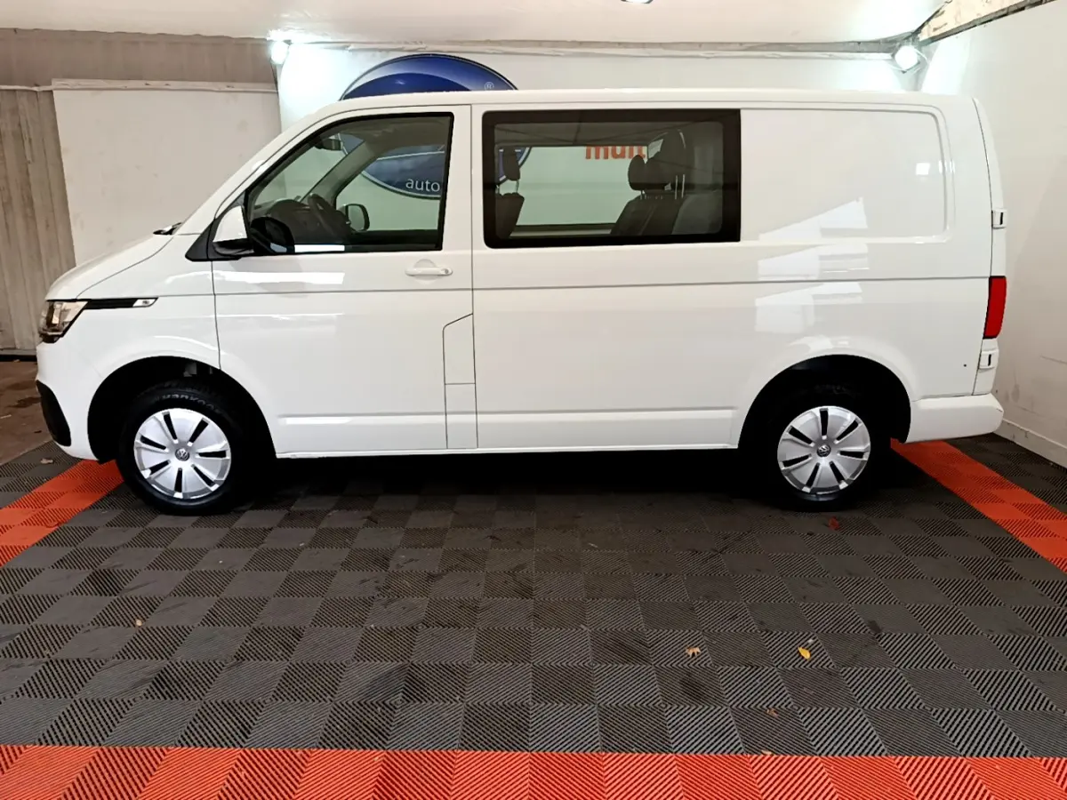 Vue de profil droit du Volkswagen Transporter blanc 2.0 TDi 150 DSG7 L1H1 Business avec vitres avant et arrière.