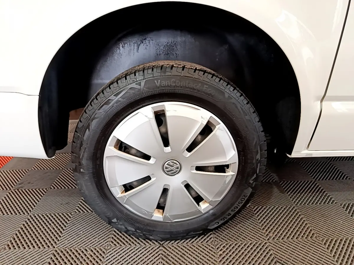 Gros plan sur la roue avant droite d'un Volkswagen Transporter blanc avec enjoliveur gris et logo VW central.