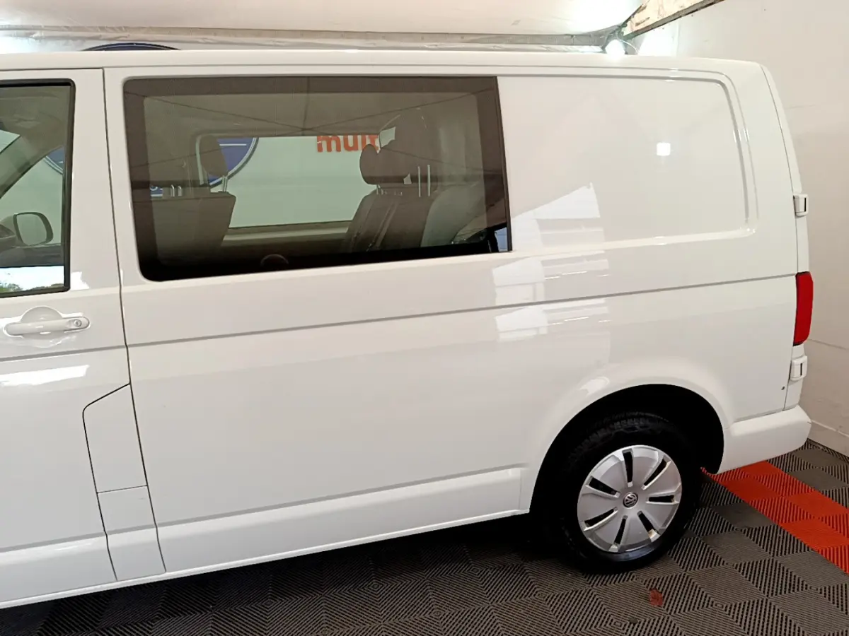 Vue latérale droite d'un Volkswagen Transporter blanc 2.0 TDi 150 DSG7 avec vitre arrière teintée et jante acier.