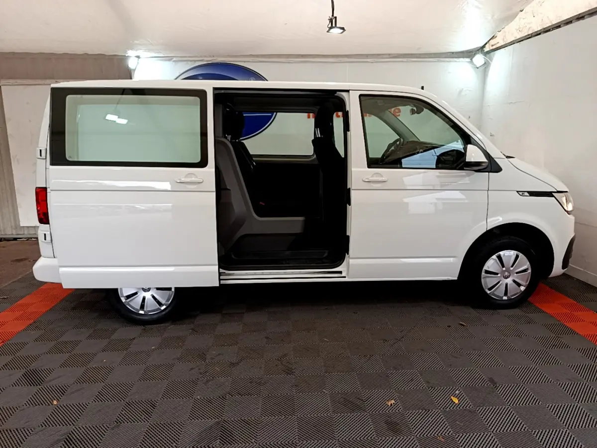 Vue latérale droite d’un Volkswagen Transporter blanc 2021 avec porte coulissante ouverte, intérieur visible.
