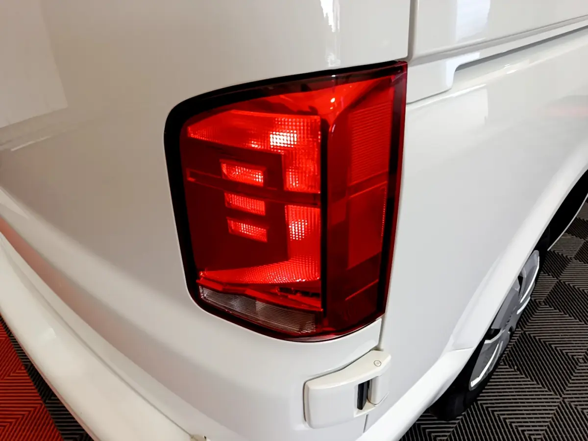 Gros plan sur le feu arrière droit rouge du Volkswagen Transporter blanc, vue arrière latérale droite.