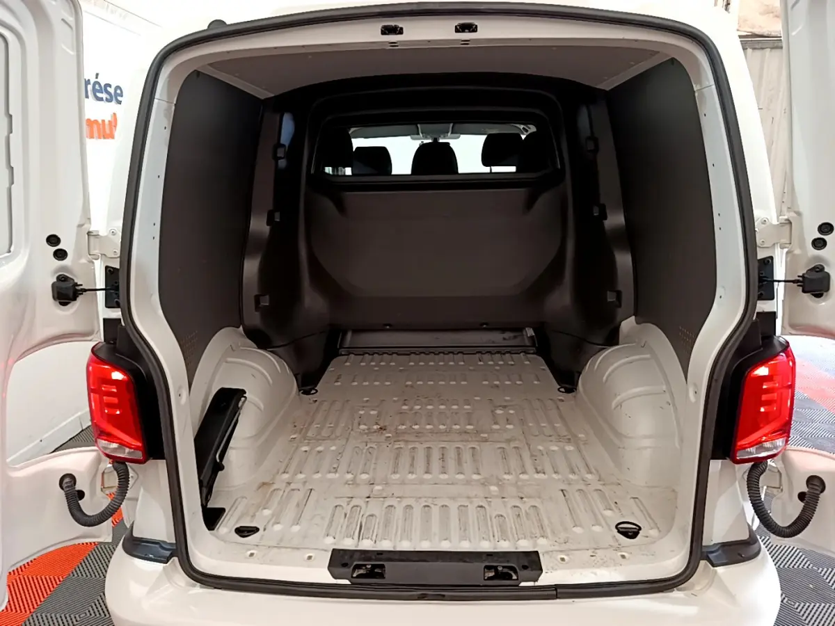 Vue arrière du Volkswagen Transporter blanc 2021 avec portes ouvertes montrant l'espace de chargement vide et la cloison pleine vitrée.
