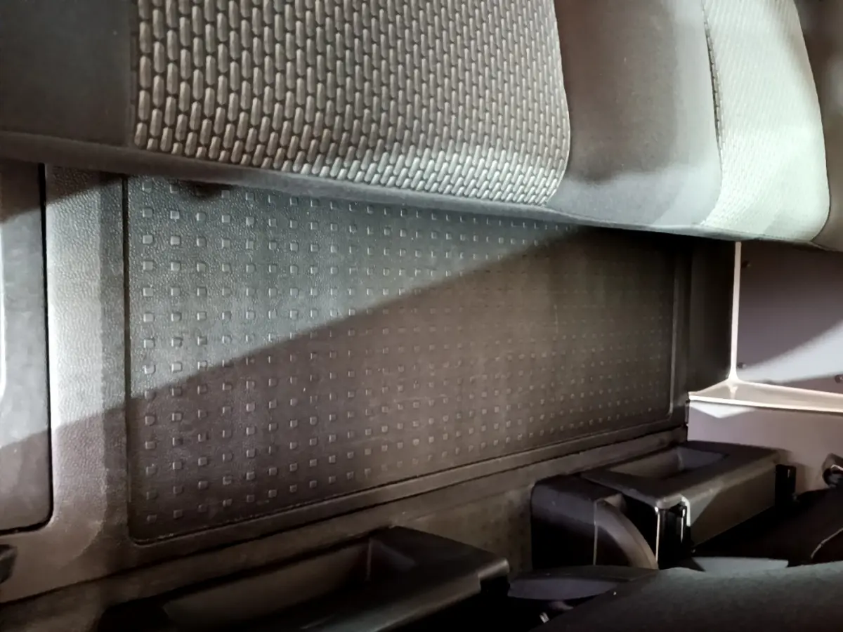 Vue intérieure du plancher arrière avec tapis caoutchouc noir et partie inférieure des sièges du Volkswagen Transporter blanc.