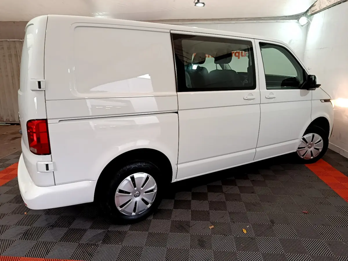 Vue latérale droite d'un Volkswagen Transporter blanc 2021 avec vitres avant teintées et jantes acier.