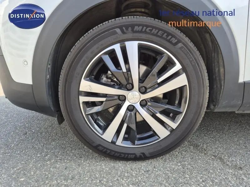 Gros plan sur la roue avant droite du Peugeot 3008 blanc nacré avec jante alliage bicolore et pneu Michelin.
