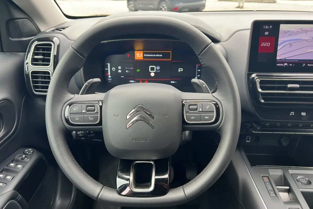 Vue intérieure centrée sur le volant cuir multifonctions d'une Citroën C5 Aircross Hybrid 2025 avec écran digital et console tactile.