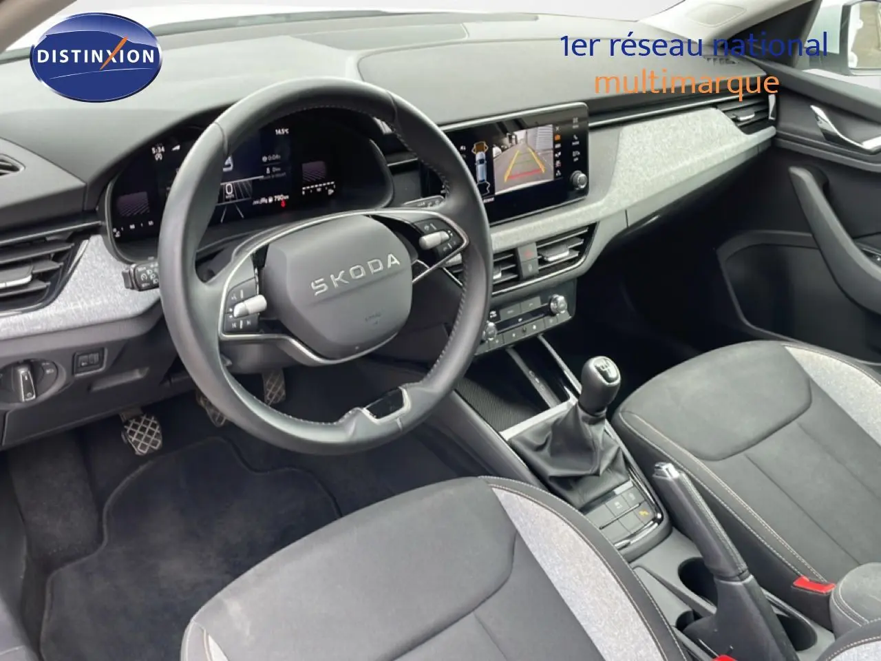 Vue intérieure côté conducteur de la Skoda Scala blanc glacier 2025, volant cuir, tableau de bord digital et levier de vitesse manuel.