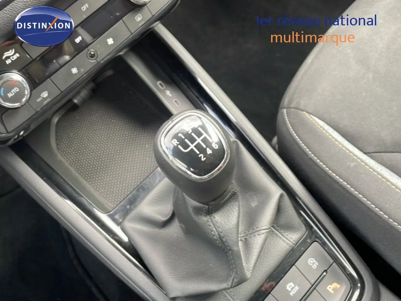 Gros plan sur la console centrale d’une Skoda Scala blanche, mettant en valeur le levier de vitesses manuel et la sellerie tissu gris noir.