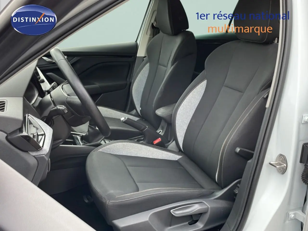 Vue intérieure côté conducteur de la Skoda Scala blanc glacier, sièges tissu gris noir avec volant multifonction.