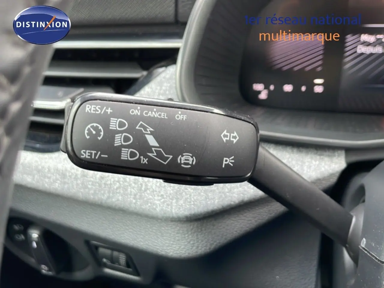 Gros plan sur la commande de régulateur de vitesse au volant d'une Skoda Scala blanc glacier, intérieur gris noir.