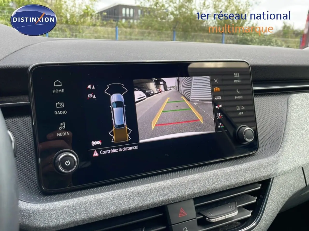 Écran tactile central affichant la caméra de recul avec vue arrière et alertes de distance dans un Skoda Scala blanc glacier.