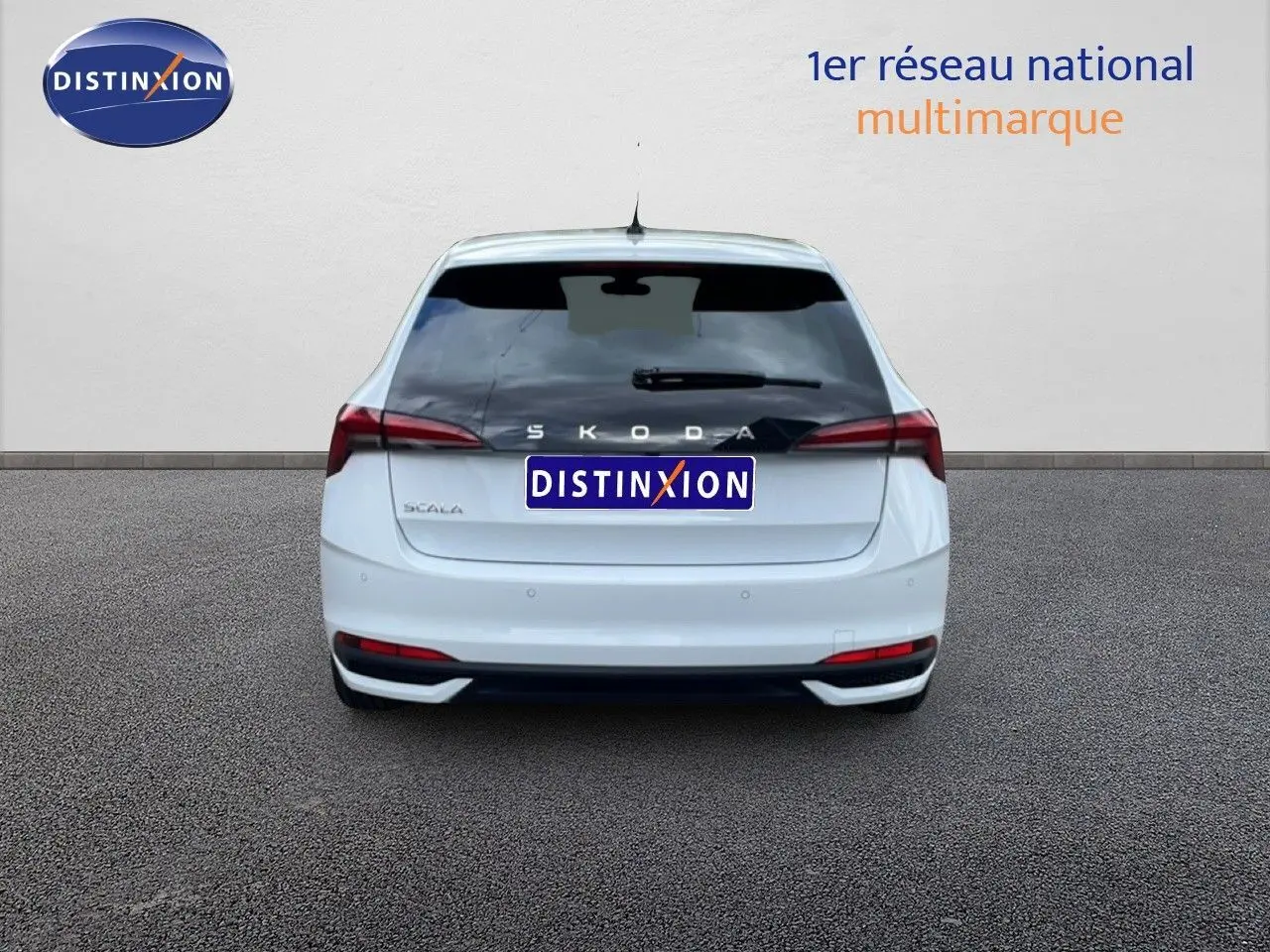 Vue arrière d'une Skoda Scala blanc glacier, avec feux arrière allongés et logo distinctif visible.