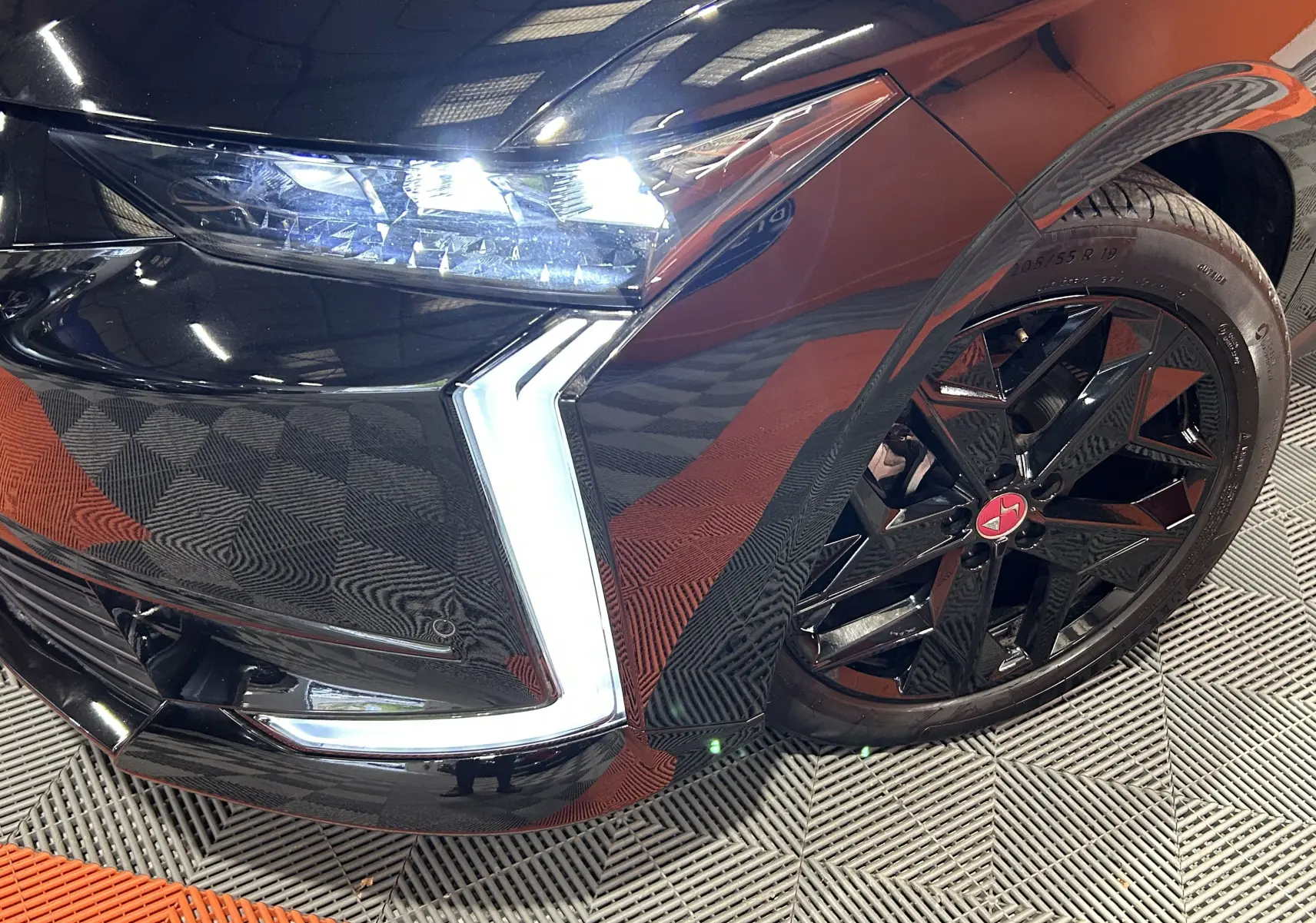 Gros plan sur l'avant droit noir Perla Nera du DS4 2024, mettant en valeur le phare LED et la jante noire à étoile rouge.