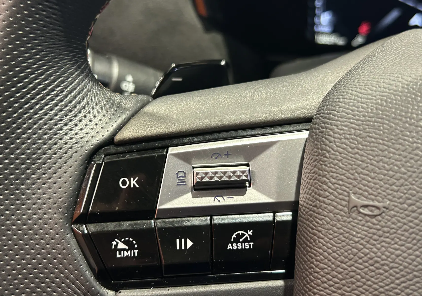 Gros plan sur les commandes au volant en cuir noir du DS4 2024, mettant en valeur les boutons d'assistance et de limitation de vitesse.