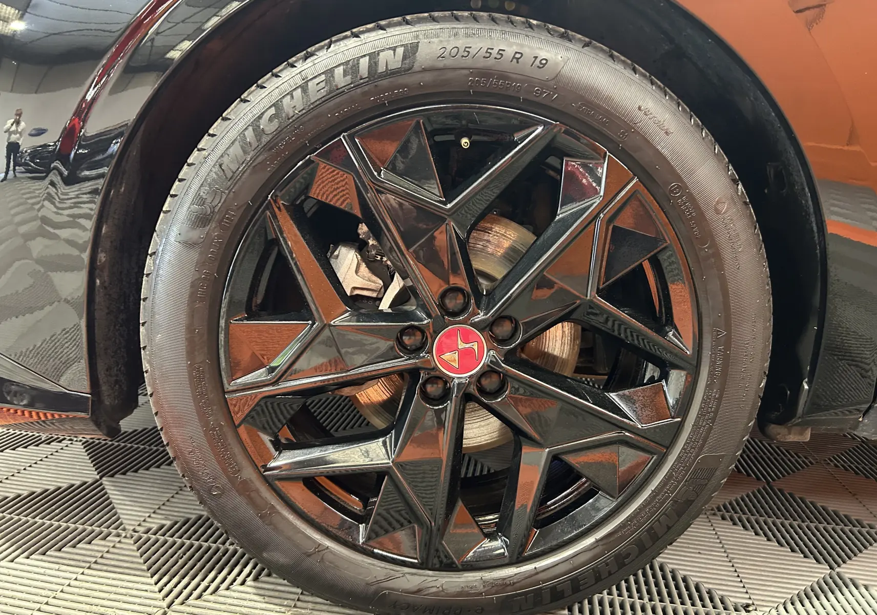 Gros plan sur la roue avant gauche noire du DS4 2024 avec jante noire à motif géométrique et logo rouge central.