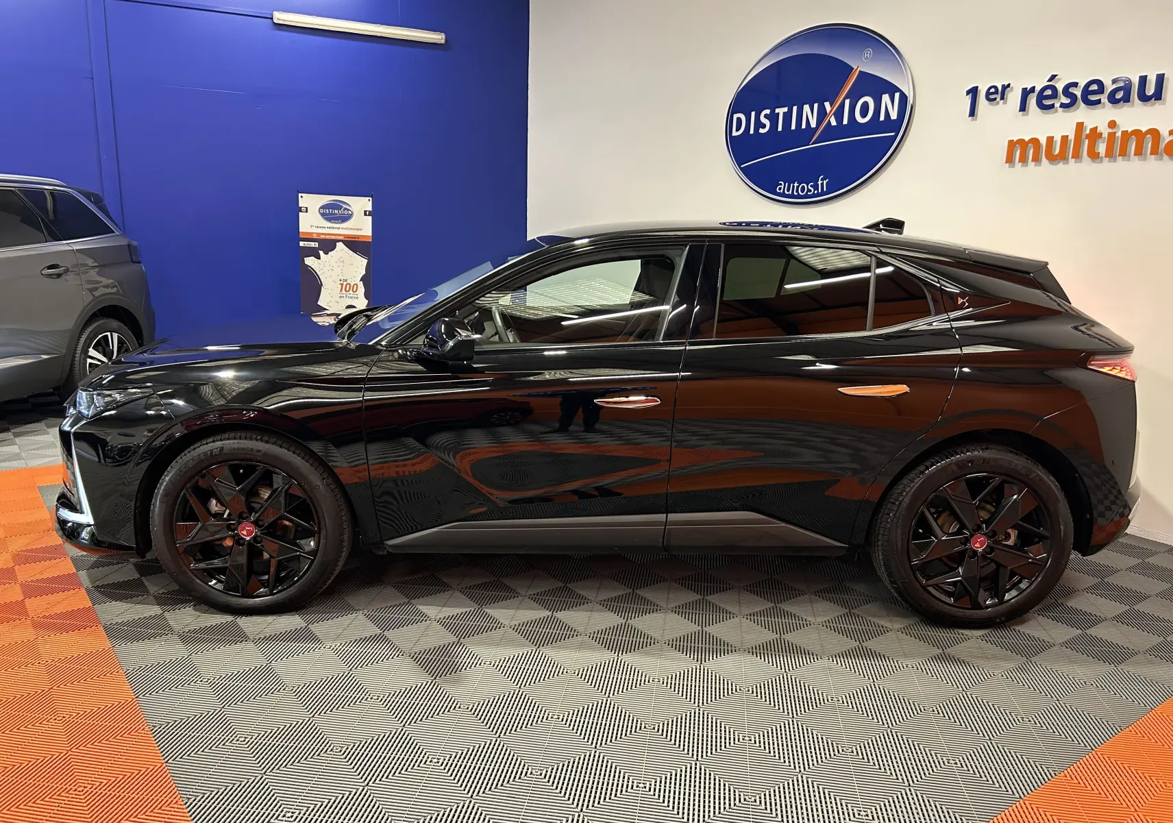 Profil côté gauche d'une DS4 2024 noir Perla Nera avec jantes noires et lignes dynamiques en showroom.