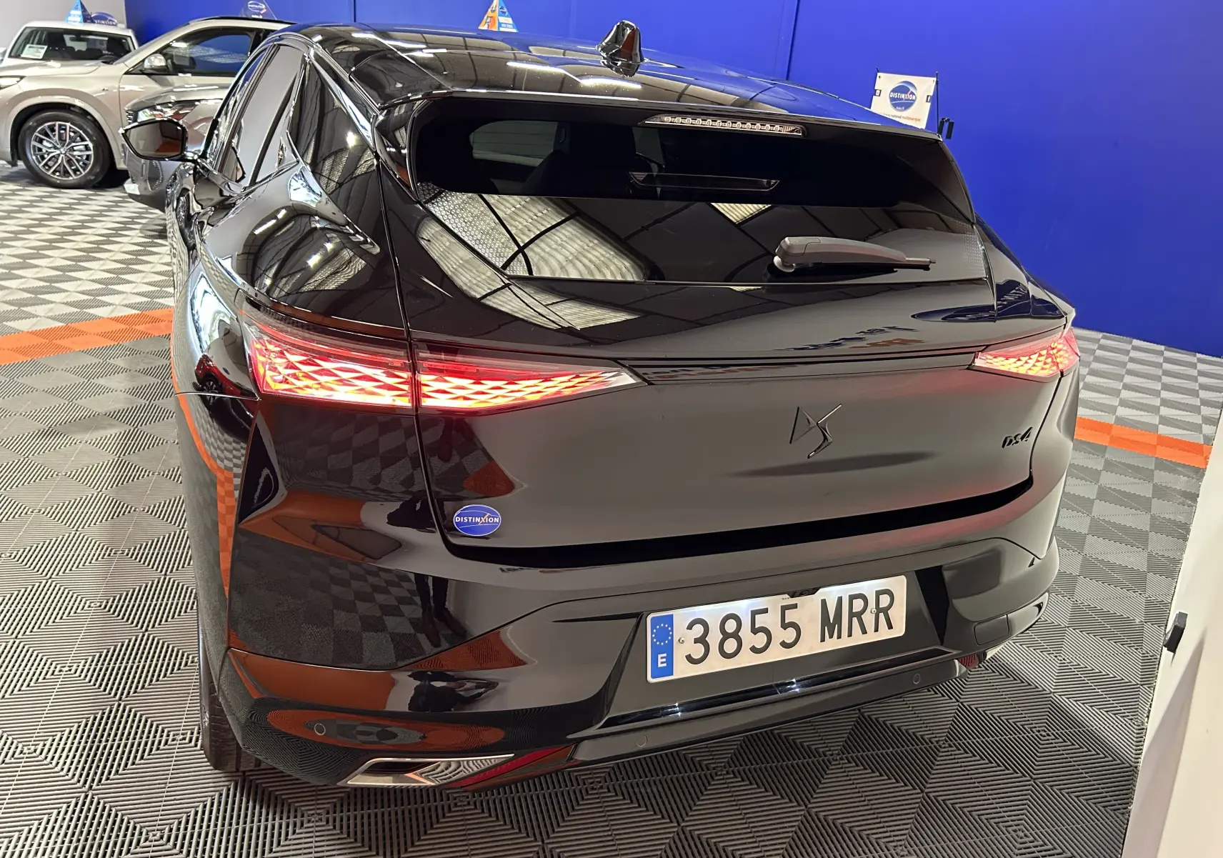 Vue 3/4 arrière droite d'une DS4 noire Perla Nera avec feux arrière LED allumés dans un showroom.