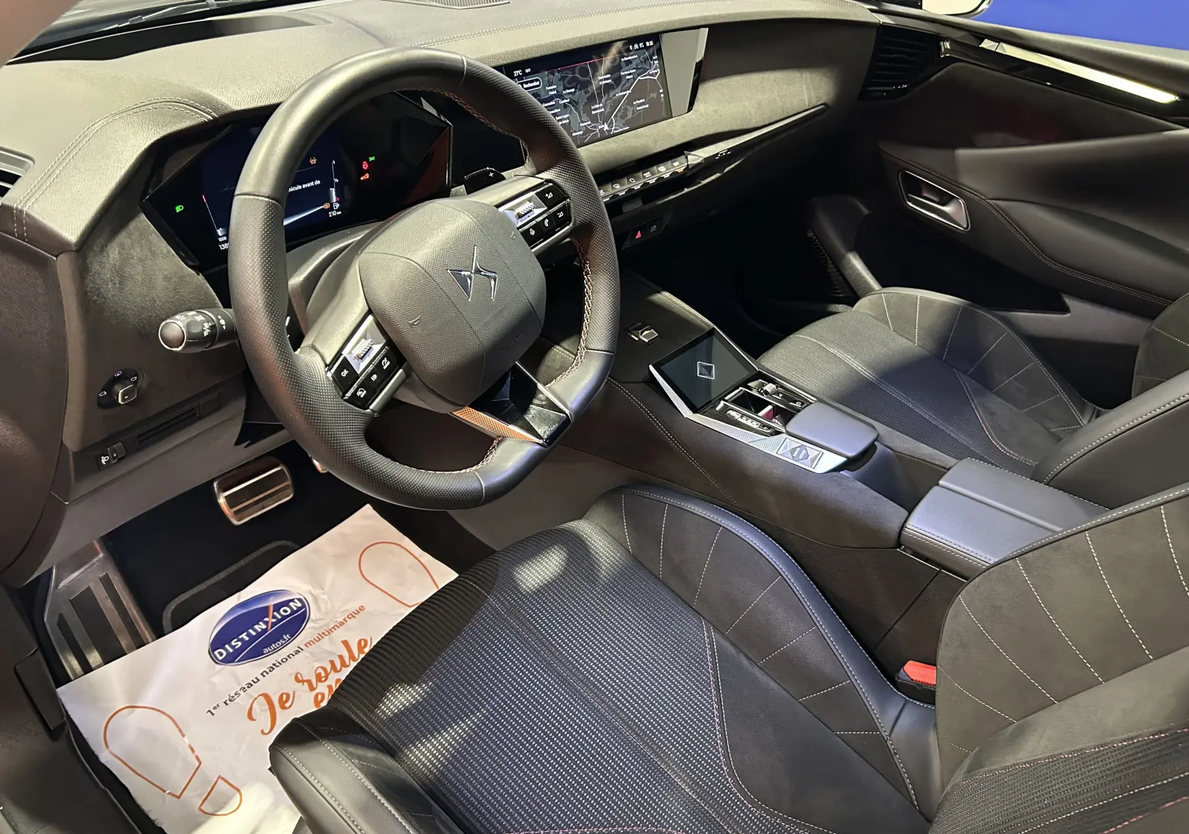 Intérieur du DS4 2024 en version Performance Line, vue côté conducteur montrant le tableau de bord et sièges noirs avec surpiqûres rouges.