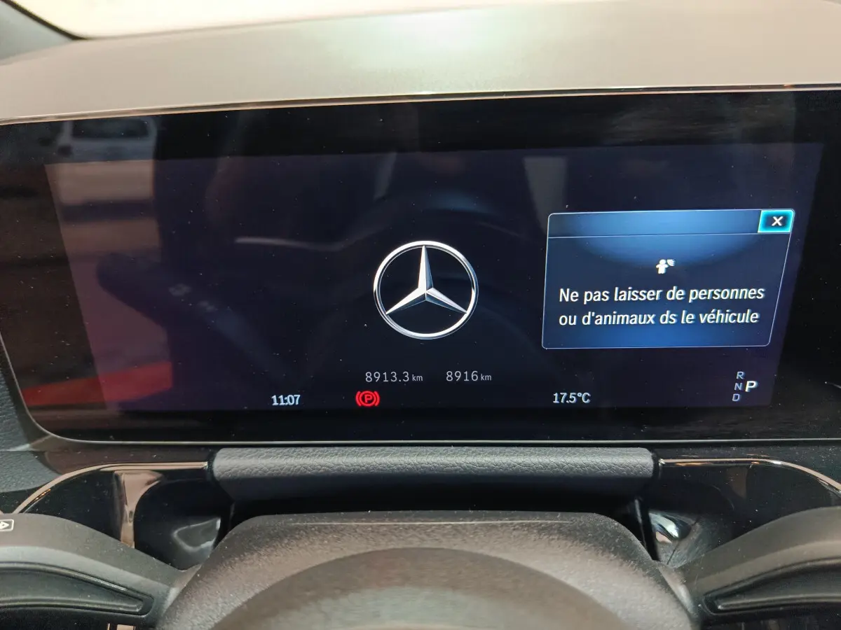 Affichage numérique du tableau de bord du Mercedes GLA 250 e bleu, avec logo central et message de sécurité.