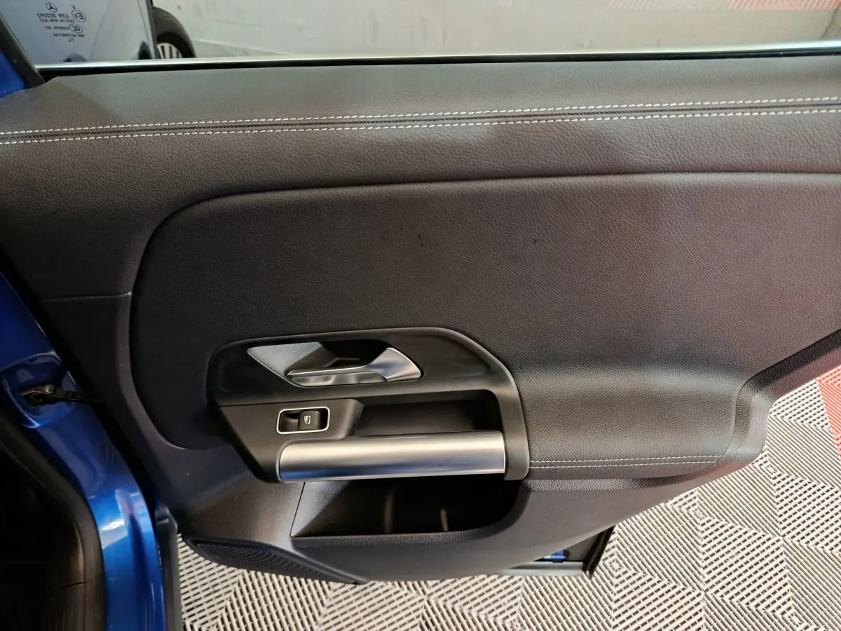 Gros plan sur la porte côté gauche bleu du Mercedes GLA 250 e Business Line avec poignée argentée et bouton de fenêtre.