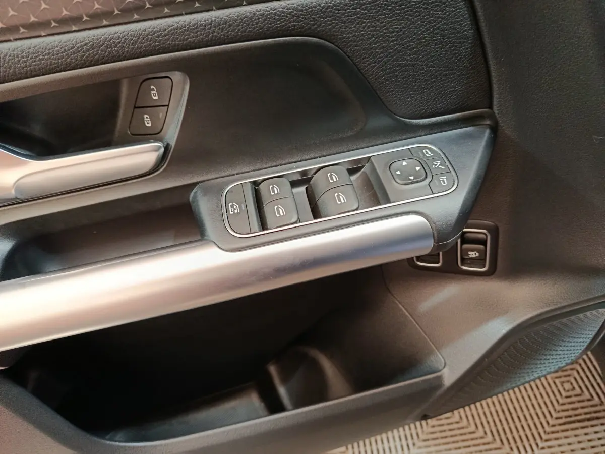 Gros plan sur la commande des vitres et rétroviseurs côté conducteur du Mercedes GLA 250 e bleu 2024.