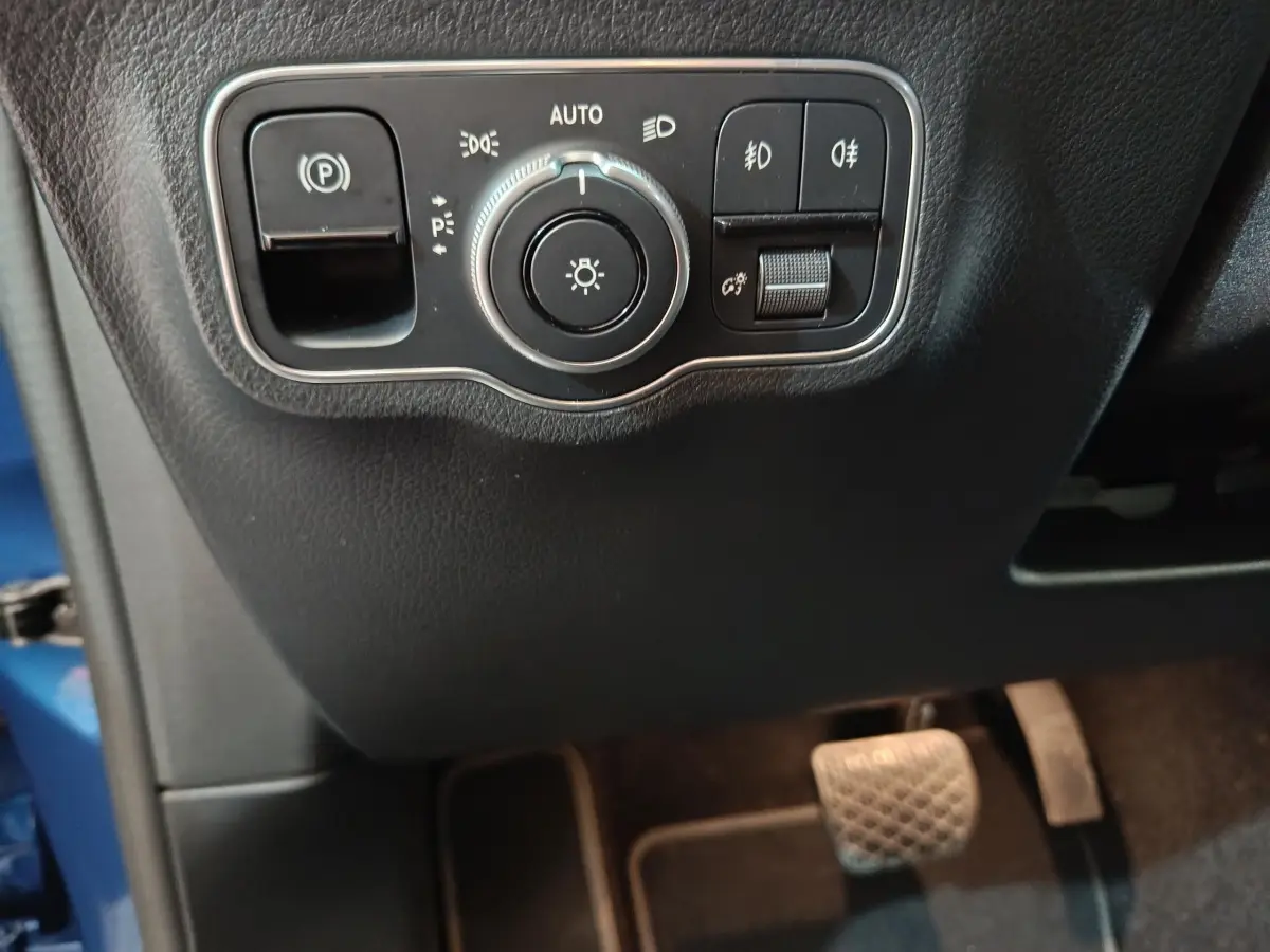 Gros plan sur les commandes d'éclairage et frein de stationnement du Mercedes GLA 250 e bleu, côté conducteur intérieur.