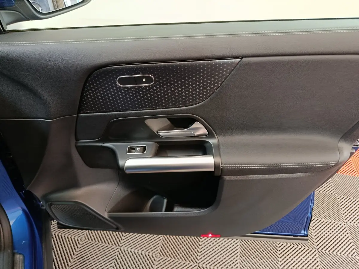Gros plan sur la porte côté gauche du Mercedes GLA bleu 2024, avec garniture noire et poignée argentée.
