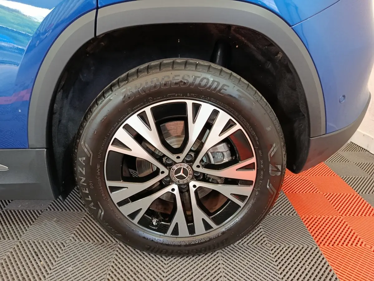 Gros plan sur la roue avant droite d’un Mercedes GLA 250 e bleu, mettant en valeur la jante alliage et le pneu Bridgestone.