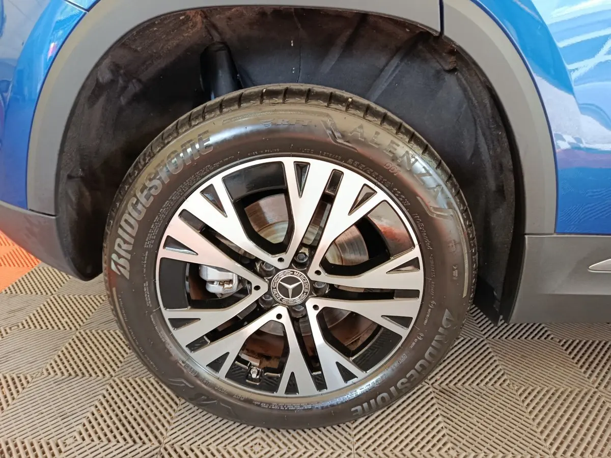 Gros plan sur la roue avant droite d'un Mercedes GLA 250 e Business Line bleu, avec jante alliage et pneu Bridgestone.