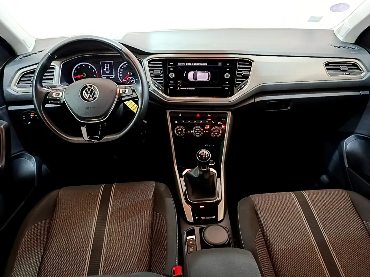 Vue intérieure frontale du tableau de bord et volant cuir noir du Volkswagen T-Roc 1.0 TSI avec boîte manuelle.