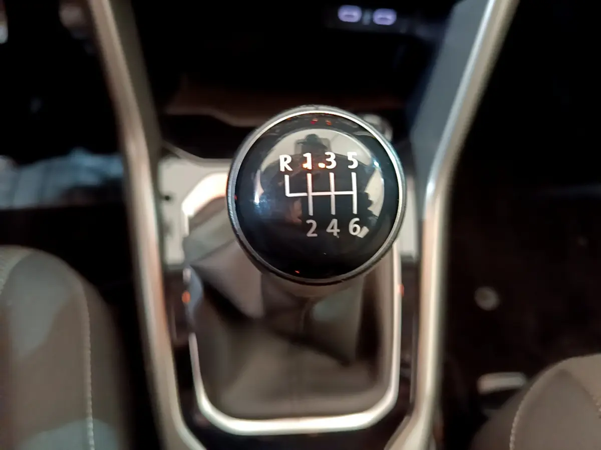 Gros plan sur le levier de vitesses manuel noir du Volkswagen T-Roc 1.0 TSI 110 Lounge, intérieur gris foncé.