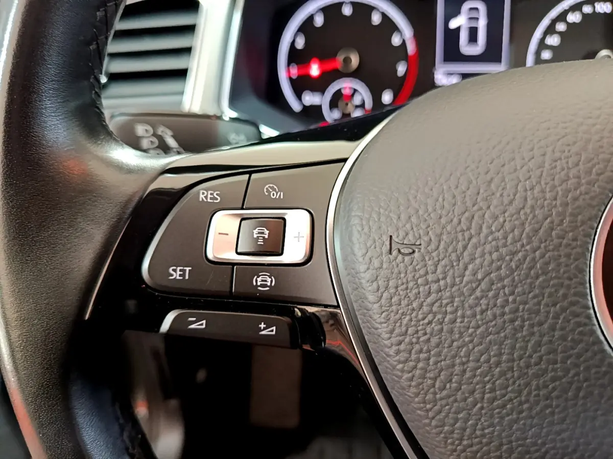 Gros plan sur le volant cuir du Volkswagen T-Roc 1.0 TSI 110 Lounge avec commandes de régulateur adaptatif.