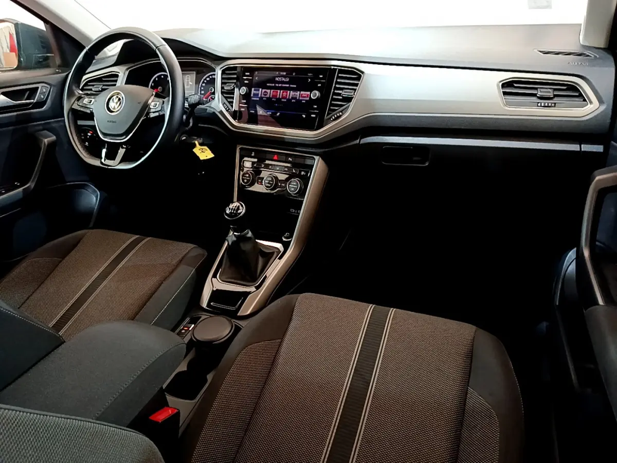 Intérieur de Volkswagen T-Roc 1.0 TSI 2021 vu côté conducteur, tableau de bord moderne avec écran tactile et volant cuir.