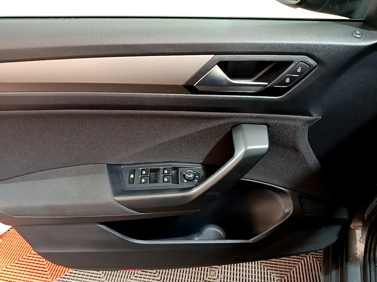 Vue intérieure du panneau de porte côté conducteur du Volkswagen T-Roc gris foncé, avec commandes des vitres et verrouillage.